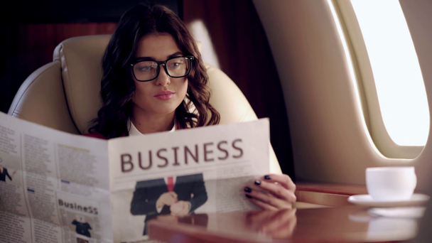 mulher de negócios séria lendo jornal de negócios enquanto viaja de avião
 - Filmagem, Vídeo