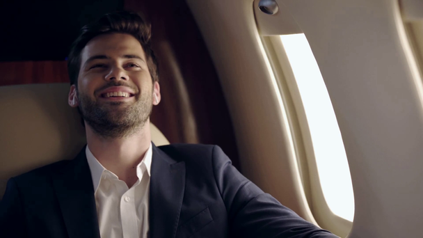 happy businessman traveling by plane and listening music in wireless earphones  - Footage, Video