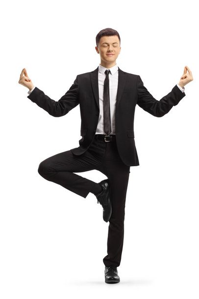 Full length portrait of a young businessman standing and meditating isolated on white background - Foto, immagini
