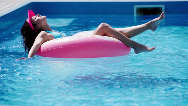 brunetka dziewczyna w pływanie na pierścień kąpielowy w basen w lecie - Materiał filmowy, wideo