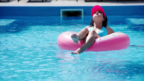 dziewczyna w pływanie na pierścień pływacki w basenie w lecie - Materiał filmowy, wideo
