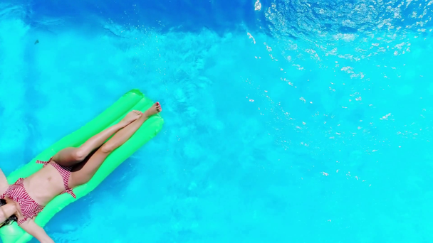 プールで休んでいるセクシーな女の子のトップビューがプールに浮かぶ - 映像、動画