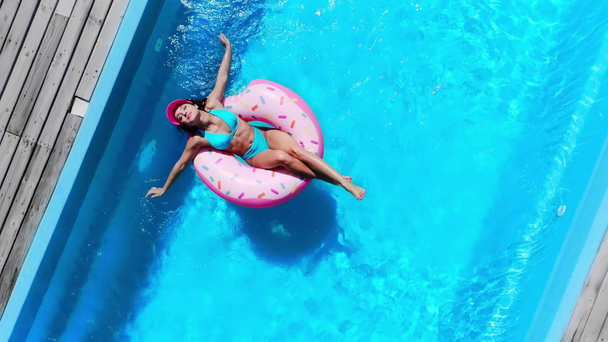 widok z góry dziewczyna relaks na pączek pierścień pływacki w basenie w lecie - Materiał filmowy, wideo
