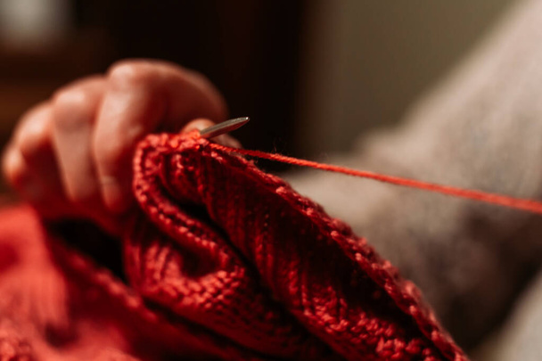 Older woman hands, knitting red sweater. Hobby and leisure - Fotó, kép