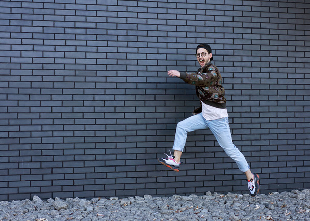 fashion guy runs and poses brick black urban background - Zdjęcie, obraz