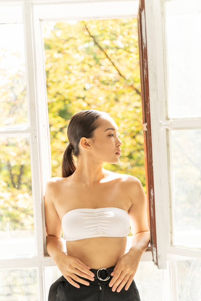 Young pretty woman standing near window indoors - Valokuva, kuva
