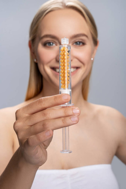 Cheerful female person demonstrating prick with serum - Foto, afbeelding