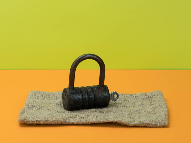 Retro lock and key on burlap on orange and green background. A bright background. - Photo, Image