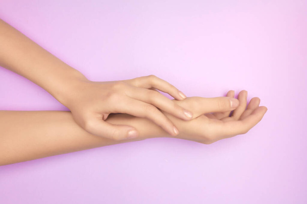 Lähikuva naisten kädet purppuranpunainen tausta. Ihonhoidon lahjakortin käsite. Herkän ihon hoito. Hellävarainen käden karvojen poisto
 - Valokuva, kuva