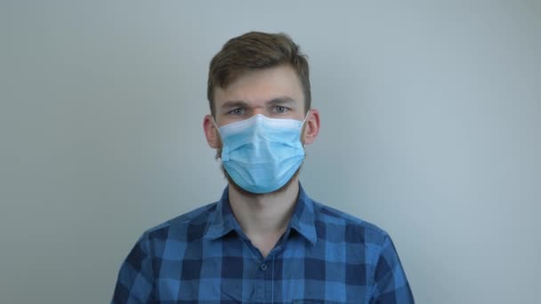 Man in medical face mask putting on protective medical cap for virus infection prevention and protection.  Portrait of young guy wearing medical cap. Pandemic protection of the Covid-19 coronavirus - Filmagem, Vídeo
