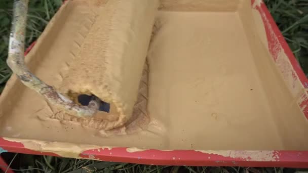 Close up of draining paint roller in bucket  - Кадри, відео