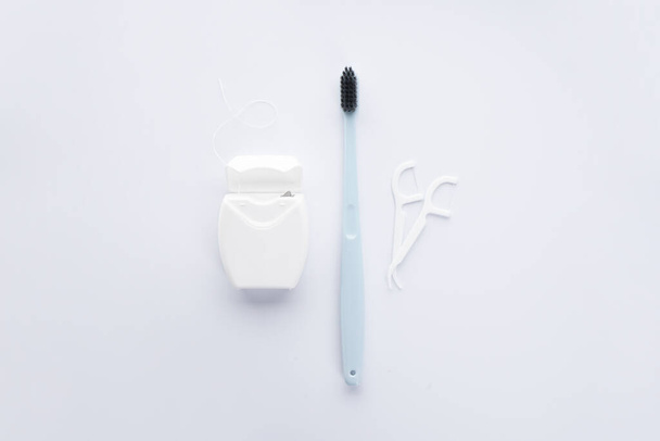 Cepillo de dientes rosa con palillo blanco y hilo dental sobre fondo blanco
. - Foto, imagen