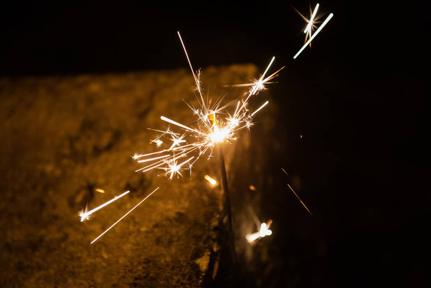 Burning sparking stick starlight fireworks pyrotechnic dark black warm background - Photo, Image