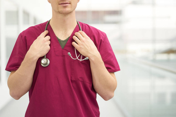 Close up caucasian man doctor with stethoscope on neck, weared in burgundy medical outfit. Copy space. - Foto, Imagem