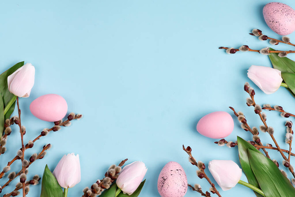 Paskalya el sanatları ile çerçevelenmiş yumurtalar, laleler açık mavi arka planda çiçekler.. - Fotoğraf, Görsel
