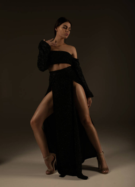 Elegant beautiful woman with long legs in black fashionable dress posing in studio on grey background. - Foto, Bild