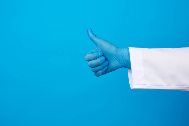 mulher médica de casaco branco, vestindo luvas de látex médico azul em suas mãos, mostrando como gesto na mão, conceito de aprovação, espaço de cópia
 - Foto, Imagem