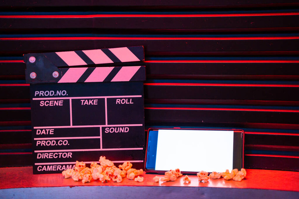 mobile phone with empty white bright screen with popcorn bucket and movie clapper board. Concept of streaming TV on internet phone. - Photo, Image