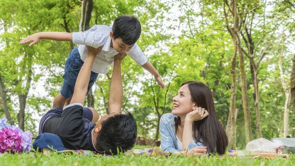 Family Picnic at gaden park Outdoors Togetherness Relaxation Concept with father carrying the kid. - Photo, Image