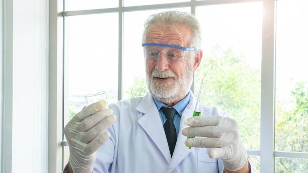 Großaufnahme des männlichen Wissenschaftlers, der einen Schlauch und ein Becherglas mit flüssiger Substanz in der Hand hält. Die Mannforschung arbeitet im Labor. - Foto, Bild