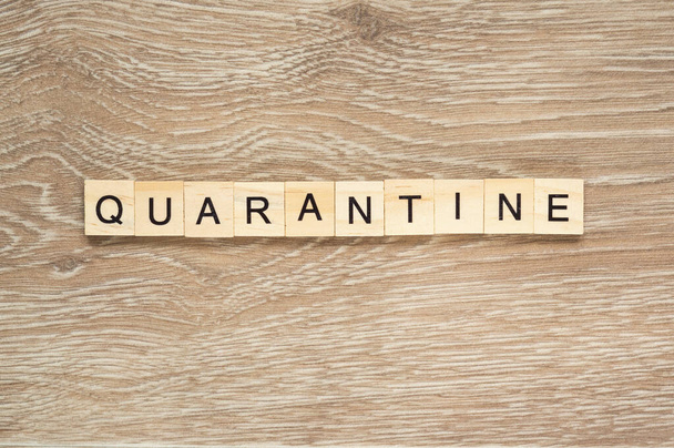 The word "Quarantine" spelt out with letter tiles on the wooden background - 写真・画像