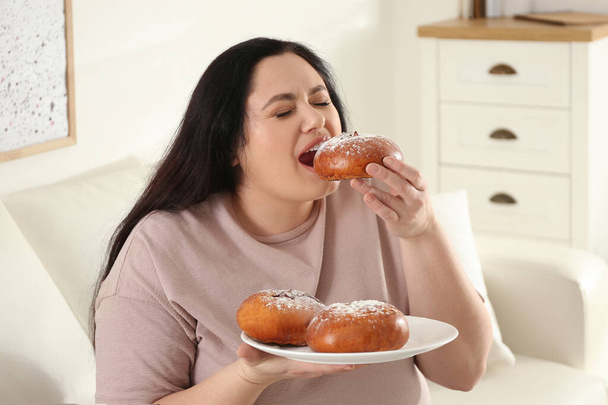 Lazy overweight woman eating buns at home - Фото, изображение