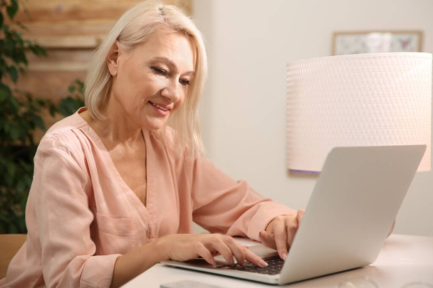Beautiful mature woman working with laptop at home - Foto, Imagem