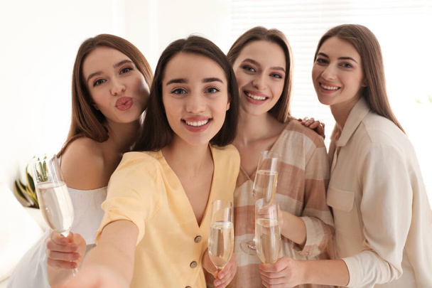 Beautiful young ladies with champagne taking selfie indoors. Woman's Day - Foto, Imagen