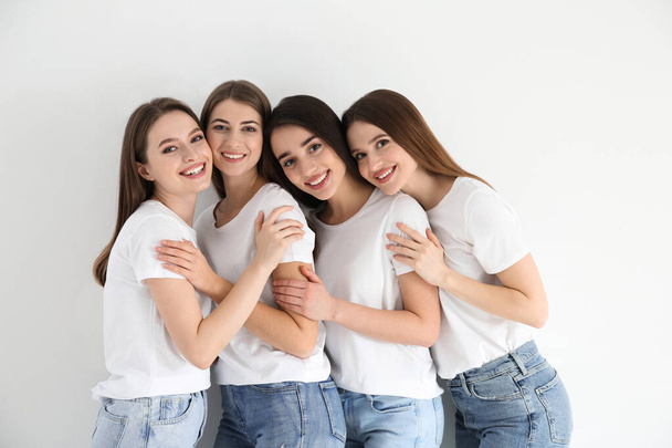 Beautiful young ladies in jeans and white t-shirts on light background. Woman's Day - 写真・画像