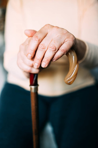 Old woman hands resting on a walking cane - Photo, Image