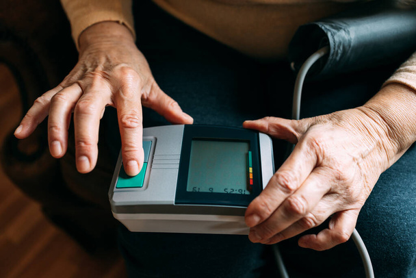 Stará žena se chystá změřit krevní tlak pomocí sfygmomanometru - Fotografie, Obrázek