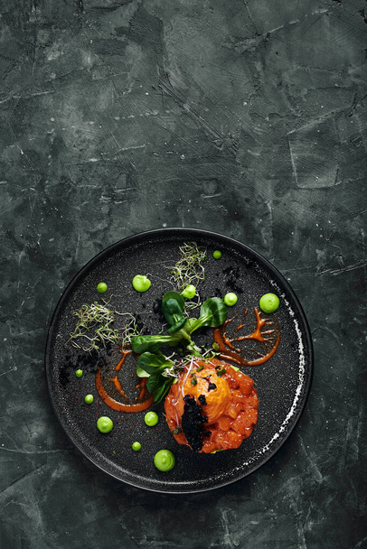 Frisches Tatar mit Lachs, Avocado, rotem Kaviar auf einem Teller, schöne Bedienung, Schöne Bedienung, traditionelle italienische Küche, grauer Hintergrund, Kopierraum. Ernährungskonzept - Foto, Bild