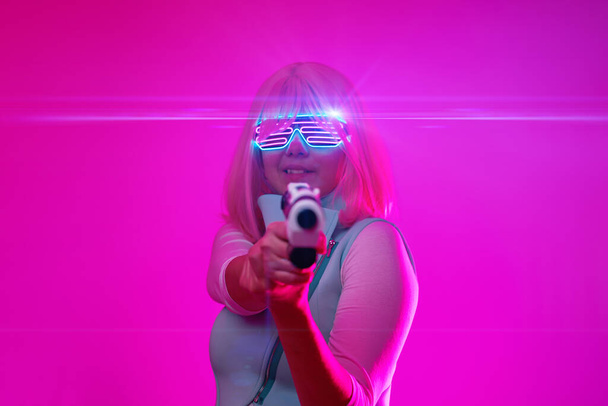 Chica con blaster en la batalla futurista. Concepto de realidad virtual, juego cibernético
. - Foto, Imagen