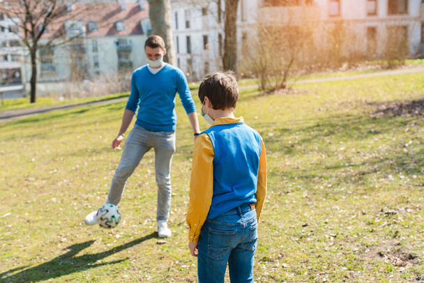 Tata i syn grali w piłkę nożną w parku podczas kryzysu koronawirusowego - Zdjęcie, obraz