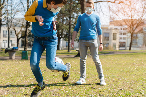 Vater und Sohn spielen während der Coronavirus-Krise Fußball im Park - Foto, Bild
