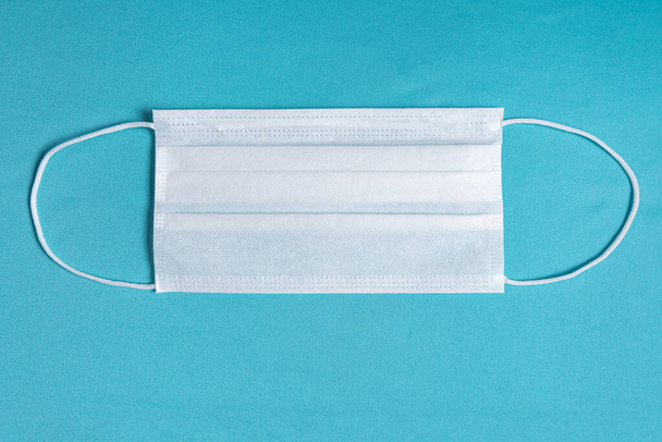 Surgical mask over minimalist blue background - Фото, зображення