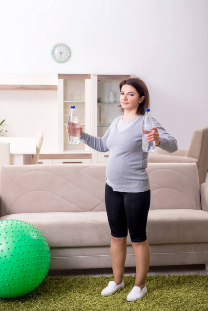 Aged pregnant woman doing exercises at home - Foto, immagini