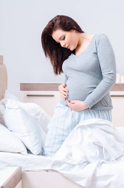 Fiatal terhes nő a hálószobában - Fotó, kép