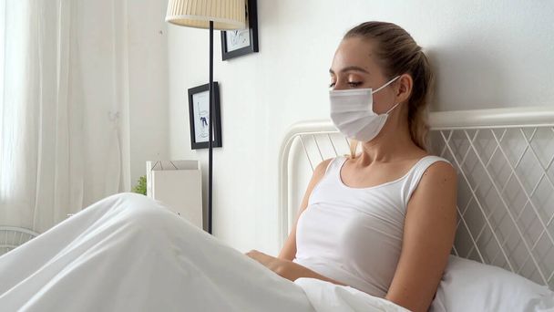 zieke vrouw draagt gezichtsbescherming masker liggend in bed heeft koorts door corona virus 2019 of COVID-19 - Foto, afbeelding