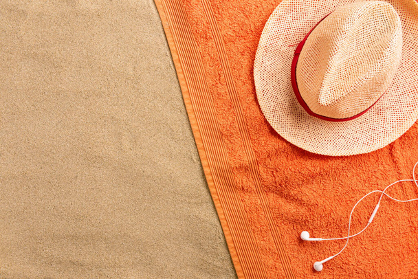 Beautiful summer holiday beach background with straw hat and headphones on sand background, border design, top view with copy space - Fotografie, Obrázek