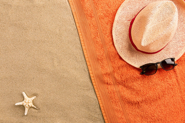 Top view straw hat and sunglasses with copy space. Traveler accessories on sand. Travel vacation concept. Summer background. Border composition made of towel - Photo, Image