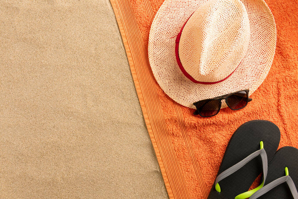 Beach towel, hat, flip flops on sand background. Minimal beach concept .Top view with copy space. - Photo, image