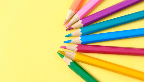 colored pencils lie on a yellow sheet of paper - Фото, изображение