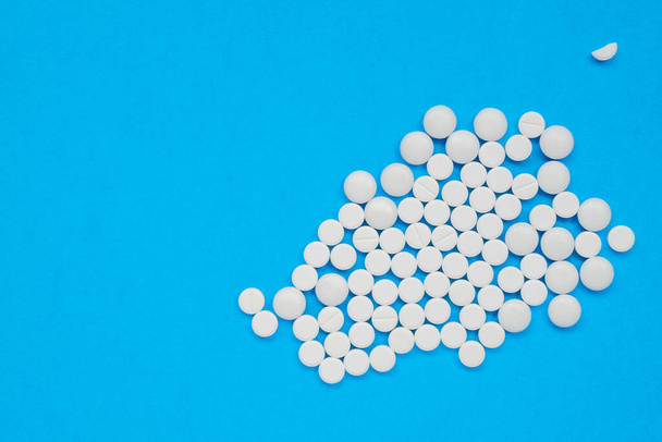 Lots of white pills on a blue background. - Photo, Image