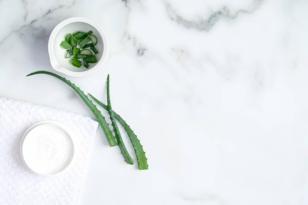 Aloe vera natural organic cosmetic cream moisturizer and sliced stems aloe vera on marble background. Flat lay, top view. Beauty product for face and hand skincare - Foto, Imagem