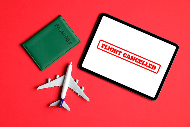 コロナウイルス(COVID-19)の概念の影響によるフライトキャンセル。飛行機のおもちゃ、パスポート、黒の背景に画面上のテキスト「フライトキャンセル」とタブレット. - 写真・画像