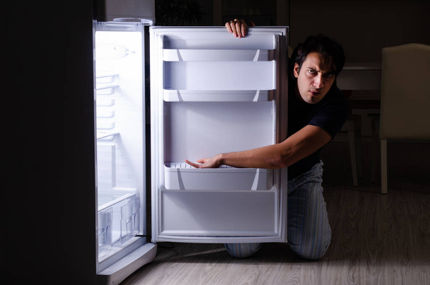 Man breaking diet at night near fridge - Foto, Imagem