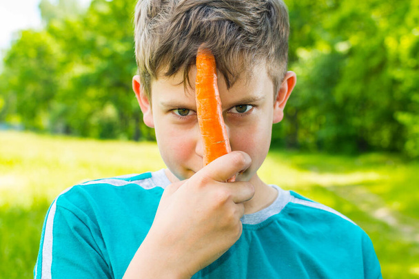 teen boy with a carrot in a forest - Photo, Image