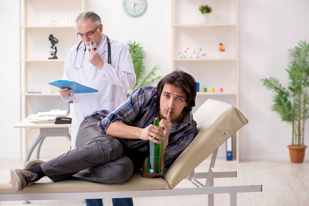 Junge männliche Alkoholiker besuchen alten Arzt - Foto, Bild