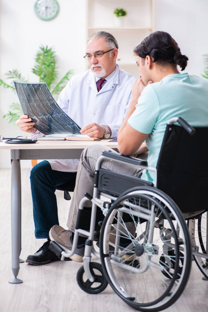 Paciente masculino em cadeira de rodas visitando médico velho
 - Foto, Imagem